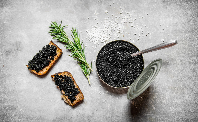Beluga caviar alternative made from eggs in a tin with toast and a sprig of rosemary