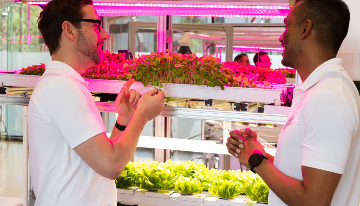 Nadun Hennayaka, CEO & Founder, and Michael Bridges, Market Research Analyst Standing in front of modular System growing leafy green plants