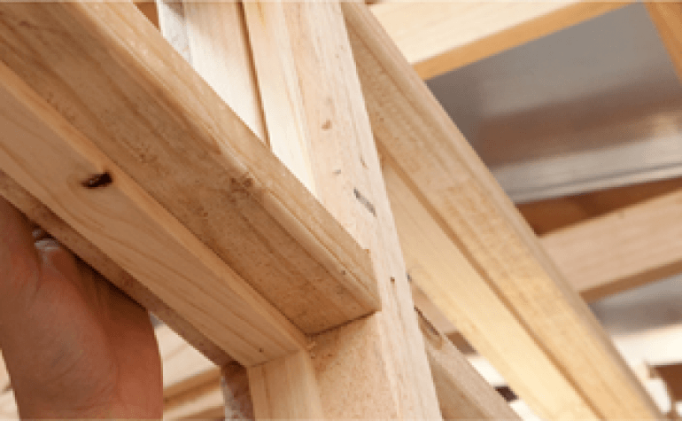 Close up image of a hand touching a internal wooded frame work