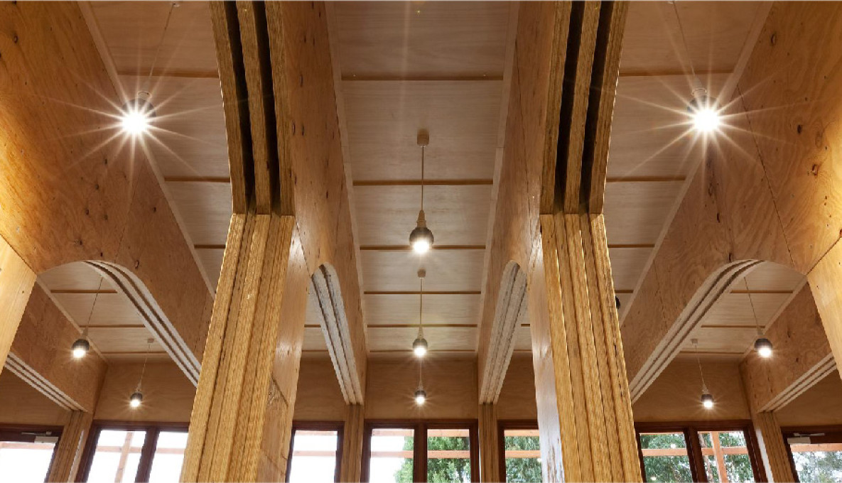 Internal shot of wood roof and poles of building